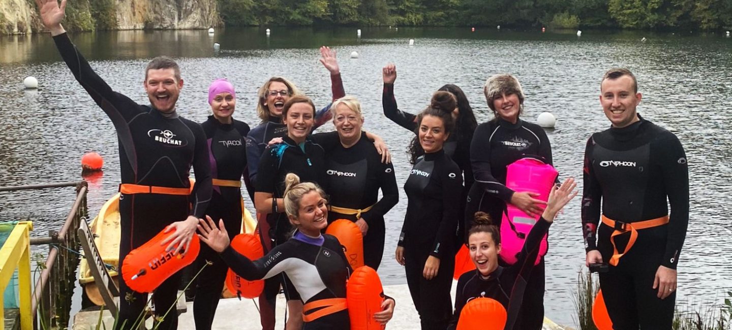 A group of WPR team members in wetsuits at a wild swimming lake