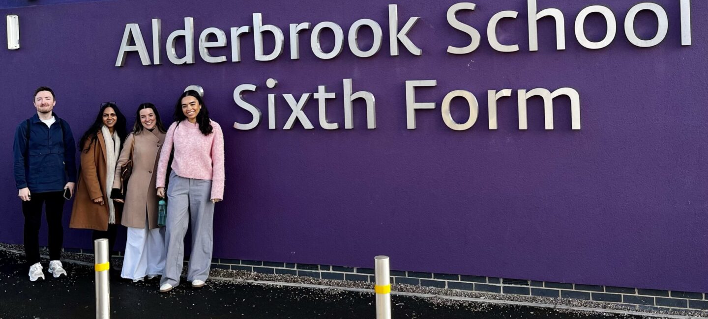 Four of the WPR team standing in front of the Alderbrook School sign