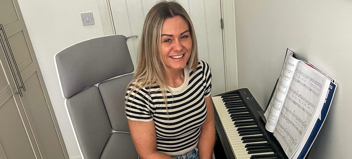 Nat sitting at a piano smiling at the camera