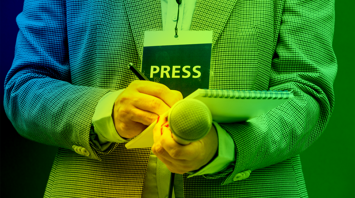 A journalist with a press pass making notes in a notebook