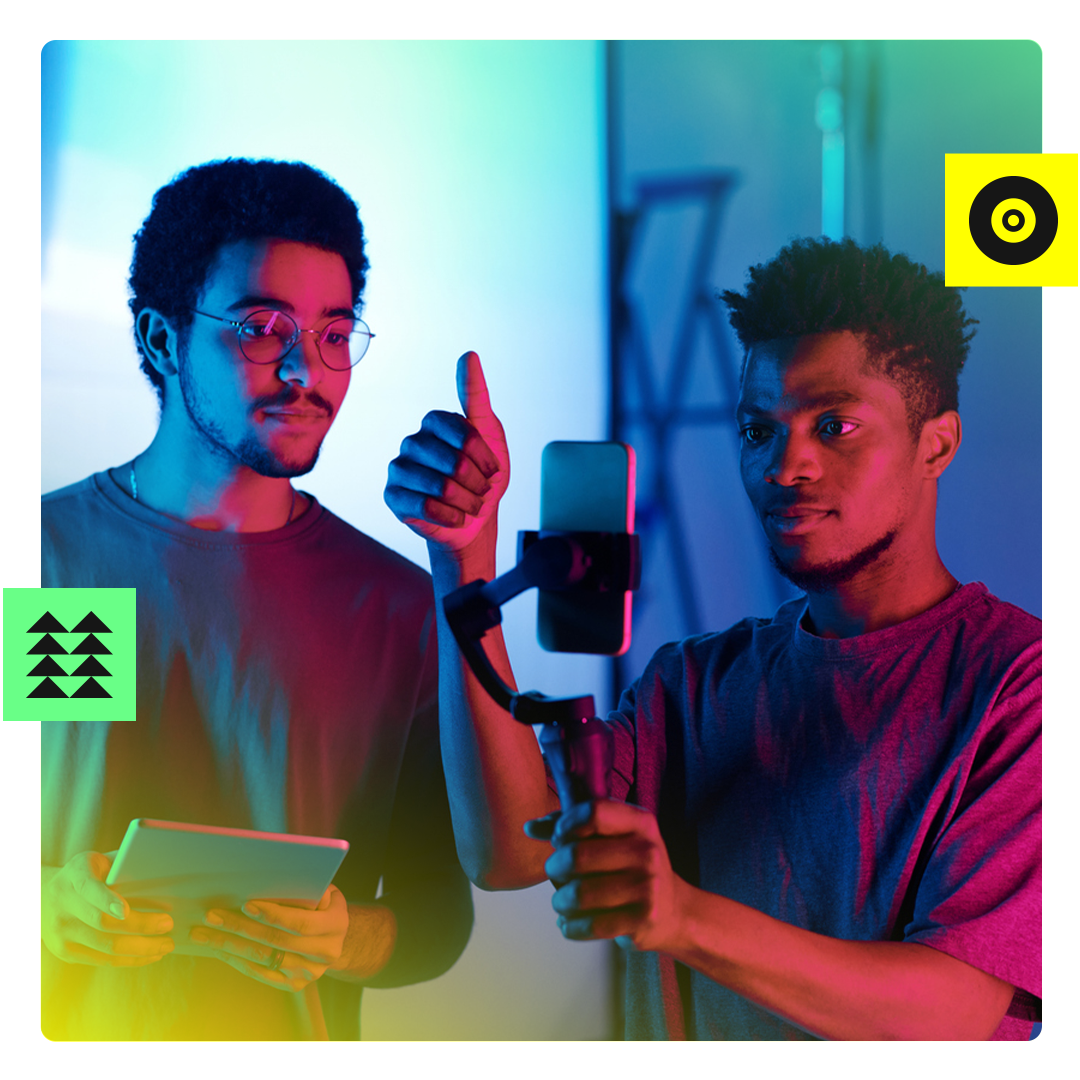 Two men looking at an iphone and giving someone off screen the thumbs up