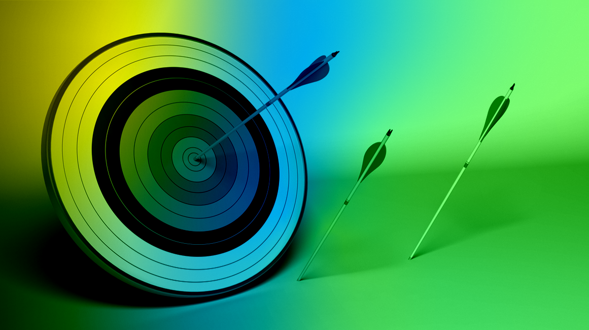 An archery target with one bullseye arrow and others that have missed